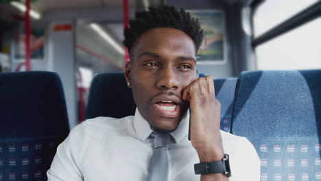 Businessman-Sitting-In-Train-Commuting-To-Work-Talking-On-Mobile-Phone