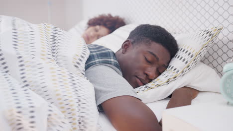 Sleeping-Young-Couple-Lying-In-Bed-At-Home-Together