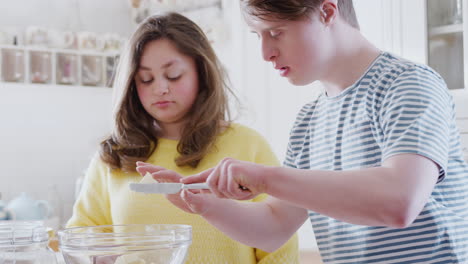 Junges-Down-Syndrom-Paar-Fügt-Butter-Zum-Kuchenrezept-Hinzu,-Das-Sie-Zu-Hause-In-Der-Küche-Backen
