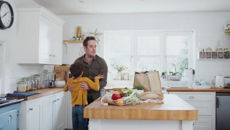 Father-And-Son-Return-Home-From-Shopping-Trip-Using-Plastic-Free-Bags-Unpacking-Groceries-In-Kitchen