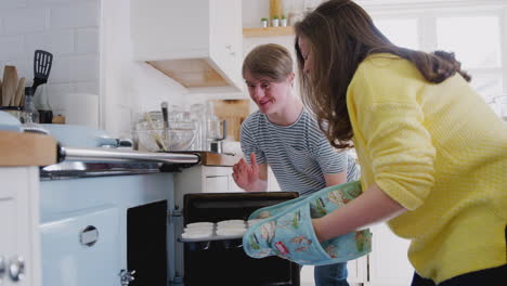 Junges-Down-Syndrom-Paar-Legt-Hausgemachte-Cupcakes-In-Den-Ofen-In-Der-Heimischen-Küche
