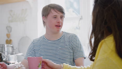 Young-Downs-Syndrome-Couple-Enjoying-Hot-Drink-In-Kitchen-At-Home