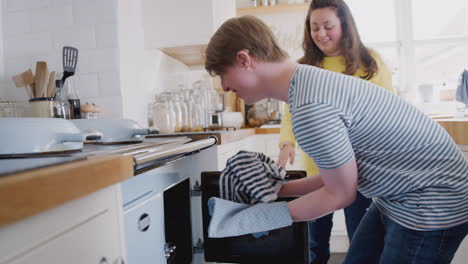 Young-Downs-Syndrome-Couple-Taking-Homemade-Cupcakes-Out-Of-Oven-In-Kitchen-At-Home