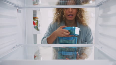 Blick-Aus-Dem-Inneren-Des-Kühlschranks,-Während-Eine-Frau-Gesunde-Lunchpakete-In-Behältern-Stapelt