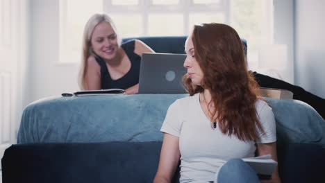 Two-Female-College-Students-In-Shared-House-Bedroom-Studying-Together