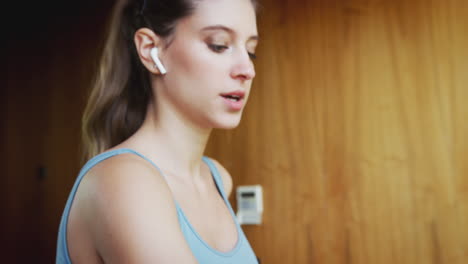 Woman-Exercising-On-Treadmill-At-Home-Wearing-Wireless-Earphones-Checking-Smart-Watch