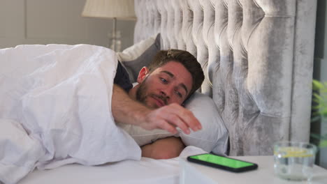 Man-Waking-Up-In-Bed-Reaches-Out-To-Turn-Off-Alarm-On-Mobile-Phone