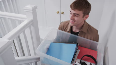 Male-College-Student-Carrying-Box-Up-Stairs-Moving-Into-Accommodation