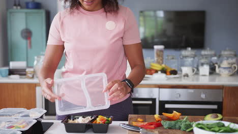 Nahaufnahme-Einer-Frau-In-Fitnesskleidung,-Die-Zu-Hause-In-Der-Küche-Eine-Reihe-Gesunder-Mahlzeiten-Zubereitet