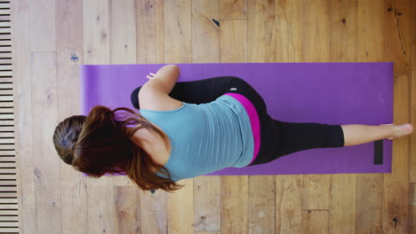 Overhead-View-Of-Young-Woman-Doing-Yoga-On-Wooden-Floor