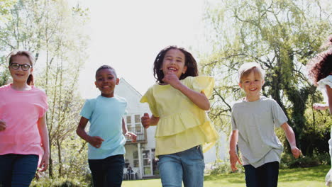 Group-Of-Children-Running-Across-Garden-Lawn-At-Home-Looking-Into-Camera
