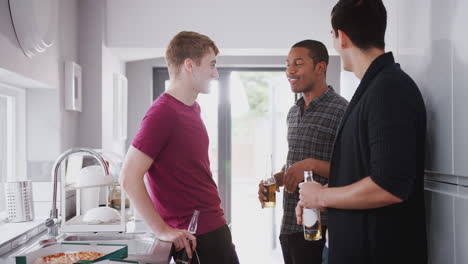 Group-Of-Male-College-Students-In-Shared-House-Kitchen-Drinking-Beer-And-Eating-Pizza-Together