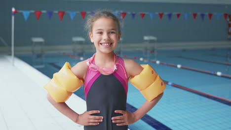 Portrait-Of-Girl-Standing-By-Edge-Of-Swimming-Pool-Ready-For-Lesson