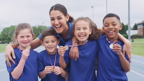 Niños-Con-Entrenadora-Mostrando-Las-Medallas-De-Los-Ganadores-En-El-Día-Del-Deporte.