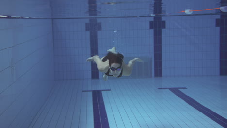 Unterwasseraufnahme-Einer-Frau,-Die-Im-Innenpool-Schwimmt