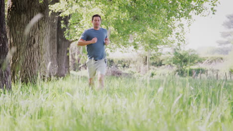 Crane-Shot-Of-Man-Exercising-Running-Through-Countryside-Field