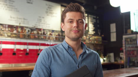 Portrait-Of-Male-Bar-Owner-Standing-By-Counter