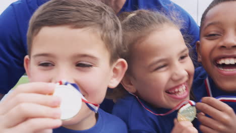 Niños-Con-Entrenador-Masculino-Mostrando-Las-Medallas-De-Los-Ganadores-En-El-Día-Del-Deporte.