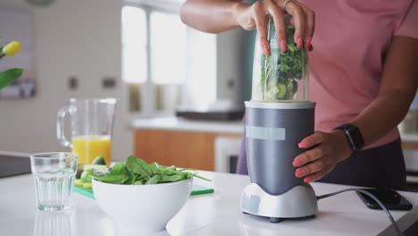Woman-Blending-Healthy-Juice-Drink-With-Fresh-Ingredients-In-Electric-Juicer-After-Exercise