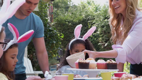 Parents-With-Children-Wearing-Bunny-Ears-Enjoying-Outdoor-Easter-Party-In-Garden-At-Home