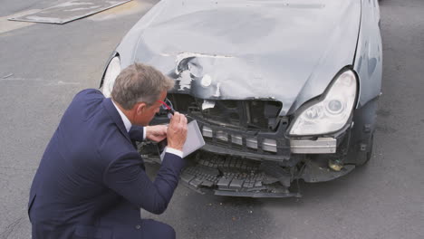 Insurance-Loss-Adjuster-Taking-Picture-With-Digital-Tablet-Of-Damage-To-Car-From-Motor-Accident
