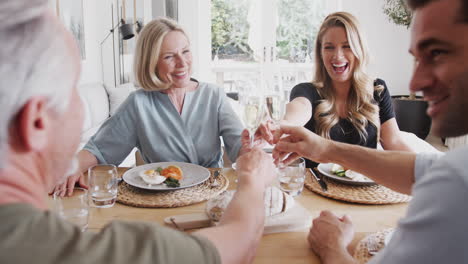Familie-Mit-älteren-Eltern-Und-Erwachsenen-Nachkommen-Stoßen-An,-Bevor-Sie-Zu-Hause-Am-Tisch-Essen