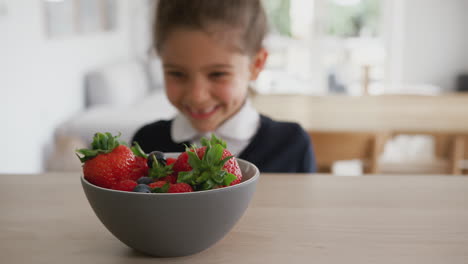 Schelmisches-Mädchen-In-Schuluniform,-Das-Erdbeeren-Von-Der-Küchentheke-Nimmt