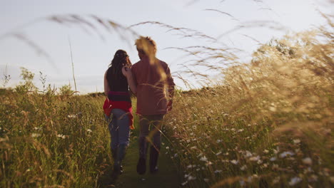 Young-Romantic-Couple-Walking-Through-Field-Towards-Teepee-On-Summer-Camping-Vacation
