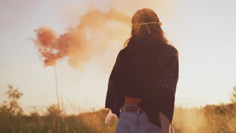 Two-Female-Friends-Camping-At-Music-Festival-Running-Through-Field-With-Smoke-Flares