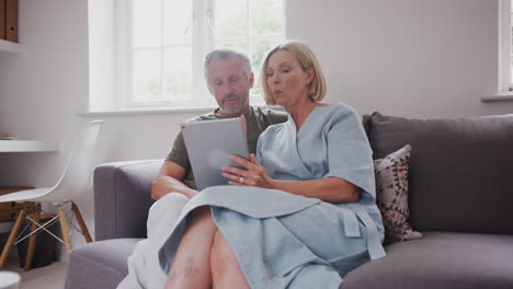 Älteres-Paar-Sitzt-Zu-Hause-Auf-Dem-Sofa-Und-Nutzt-Gemeinsam-Ein-Digitales-Tablet
