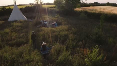 Drone-Shot-Of-Two-Mature-Women-Camping-In-Teepee-In-Field-Meeting-With-Friends