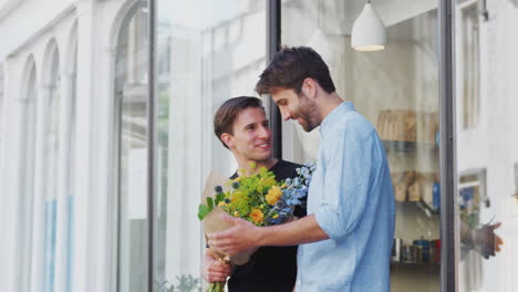 Liebevolles-Männliches-Schwules-Paar,-Das-Händchen-Hält-Und-Aus-Einem-Floristen-Kommt,-Der-Einen-Blumenstrauß-Hält