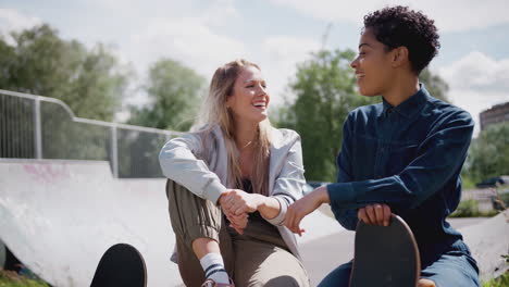 Two-Female-Friends-Talking-And-Laughing-In-Urban-Skate-Park