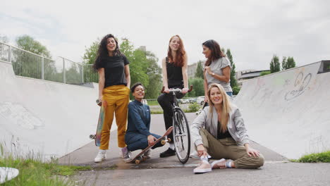 Porträt-Von-Freundinnen-Mit-Skateboards-Und-Fahrrad,-Die-Im-Städtischen-Skatepark-Stehen