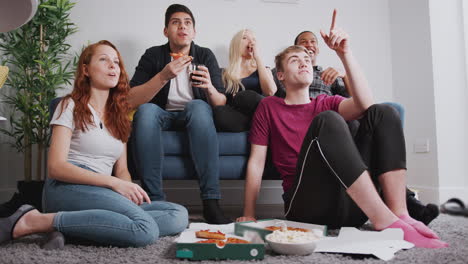 Gruppe-Von-College-Studenten-Im-Gemeinsamen-Haus,-Die-Fernsehen-Und-Pizza-Essen