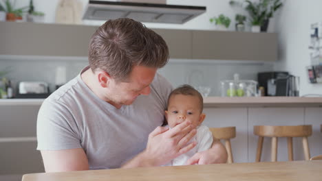 Loving-Father-Holding-3-Month-Old-Baby-Daughter-In-Kitchen-At-Home