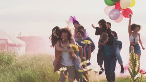 Gruppe-Aufgeregter-Junger-Freunde,-Die-Mit-Fackeln-Und-Luftballons-Durch-Das-Musikfestivalgelände-Laufen