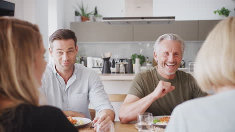 Family-With-Senior-Parents-And-Adult-Offspring-Eating-Meal-Around-Table-At-Home-Together