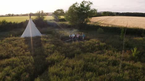 Drone-Shot-Of-Mature-Friends-Standing-Around-Fire-Singing-Songs-At-Outdoor-Campsite