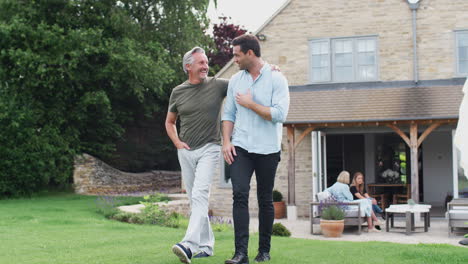 Senior-Father-With-Adult-Son-Walking-And-Talking-In-Garden-Together