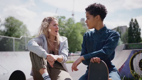 Zwei-Freundinnen-Reden-Und-Lachen-Im-Städtischen-Skatepark