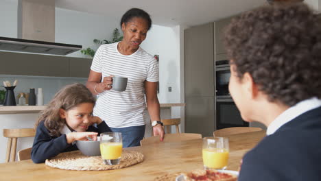 Grandparents-Sitting-In-Kitchen-With-Grandchildren-Eating-Breakfast-Before-Going-To-School