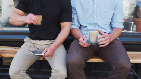 Close-Up-Of-Two-Men-Sitting-Outside-Coffee-Shop-Drinking-Coffee