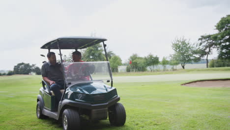 Zwei-Männliche-Golfer-Fahren-Golfbuggy-Entlang-Des-Golfplatzes-Zum-Green