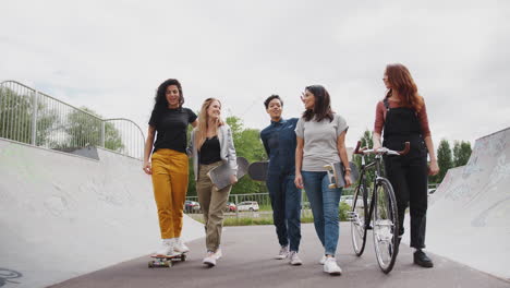 Freundinnen-Mit-Skateboards-Und-Fahrrad-Laufen-Durch-Den-Städtischen-Skatepark