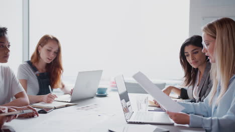 Team-Of-Young-Businesswomen-Meeting-Around-Table-Discussing-Document-Or-Plan-In-Modern-Workspace