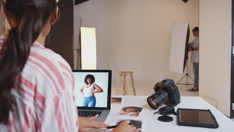 Professional-Female-Photographer-Working-In-Studio-With-Assistants-In-Background