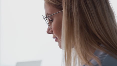Close-Up-Of-Young-Businesswoman-Wearing-Glasses-Working-On-Laptop-At-Desk-In-Modern-Workplace