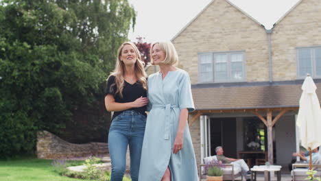 Senior-Mother-With-Adult-Daughter-Walking-And-Talking-In-Garden-Together