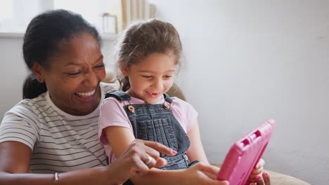 Großmutter-Sitzt-Mit-Enkelin-Im-Stuhl-Und-Nutzt-Gemeinsam-Ein-Digitales-Tablet